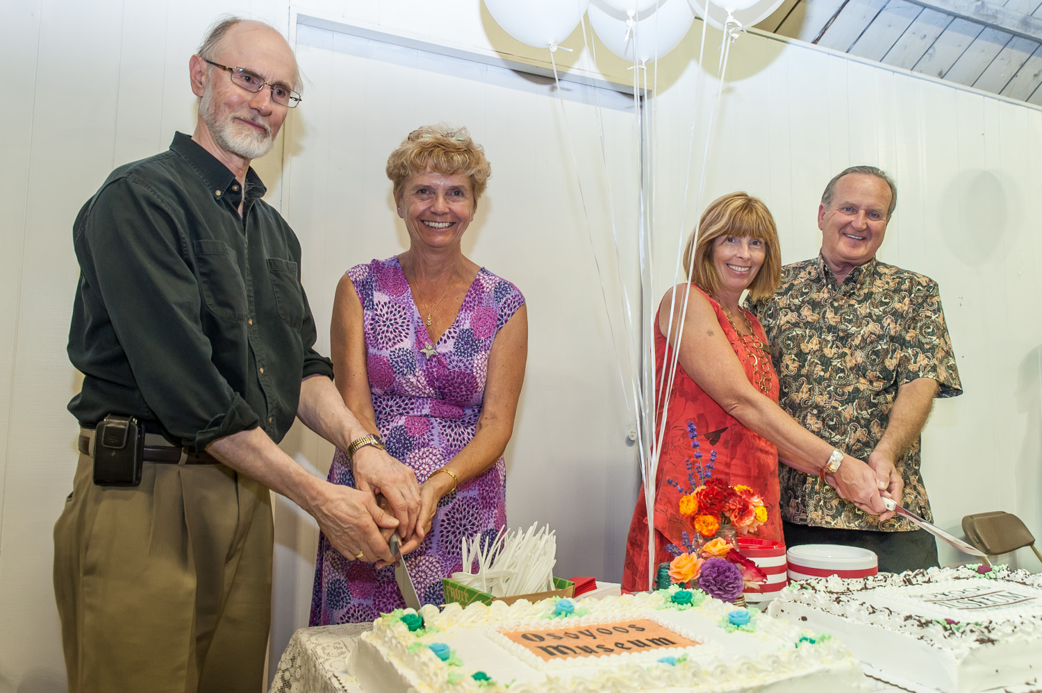 As the Osoyoos Museum and Archives celebrated its 50th anniversary, dignitaries performed a ceremonial cake cutting of cakes with the original and current museum logos. From left are federal MP Alex Atamanenko, provincial MLA Linda Larson, fundraising chair Martha Collins and Mayor Stu Wells. Photo by Richard McGuire, Osoyoos Times.