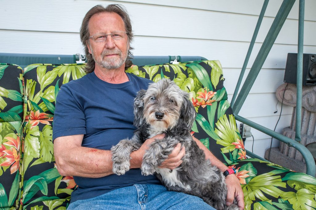 Rick Deis sits with PoopyBear, a 16-year-old dog that is frail, arthritic and partially deaf. PoopyBear was savagely attacked by a vicious pit bull and required staples to close her deep puncture wounds. The pit bull’s owner blamed PoopyBear. (Richard McGuire photo)