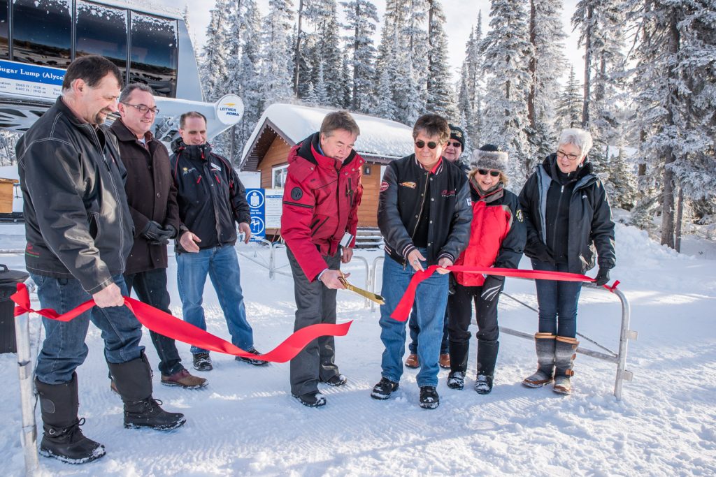 Fred Johnston, president of Baldy Capital Corporation, cuts the ribbon to officially open Mount Baldy Ski Resort to the public. He is helped by Chief Clarence Louie, of the Osoyoos Indian Band. From left are Mark Pendergraft, chair, Regional District of Okanagan-Similkameen; Oliver Mayor Ron Hovanes; Mountain Manager Matt Koenig; Johnston; Louie; Myers Bennett, president of the South Okanagan Chamber of Commerce; Judy Miller-Bennett, president of Rotary Club of Osoyoos and wife of Bennett; and Gail Scott, managing director of Destination Osoyoos. (Richard McGuire photo)