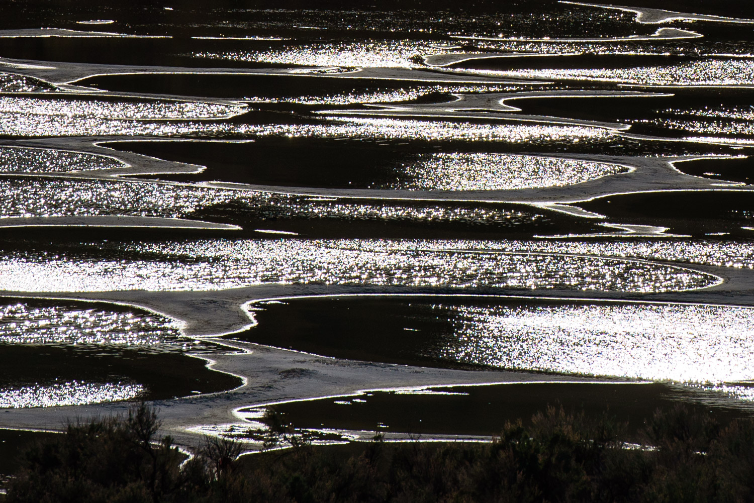 Late day sun rays glisten on the waters of Spotted Lake, framed by rings of mineral-rich mud. The lake is sacred to the Okanagan First Nations of the area. (© Richard McGuire)