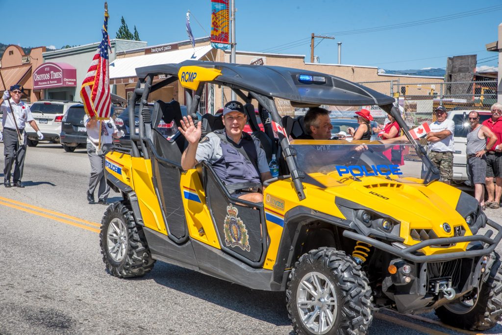 Constable Bruce Stangl waves while Corporal Jason Bayda drives the RCMP all-terrain vehicle near the front of the Cherry Fiesta parade. (Richard McGuire photo)