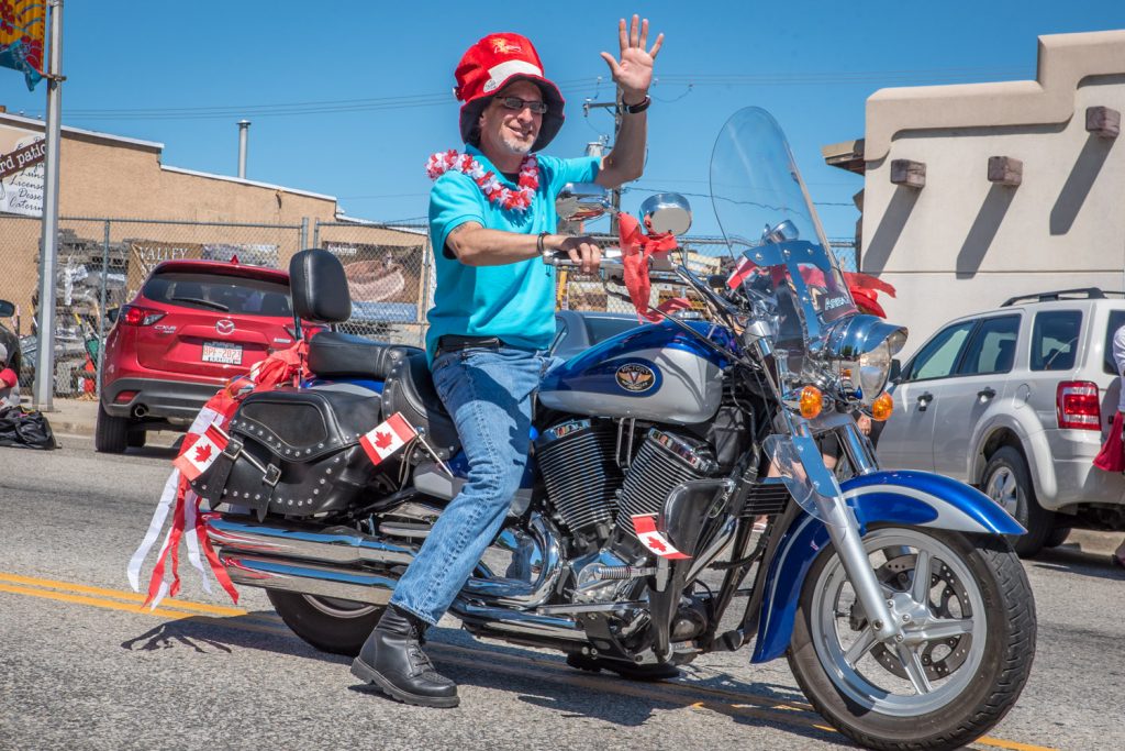 Councillor Mike Campol waves from his motorcycle in the Cherry Fiesta parade. (Richard McGuire photo)