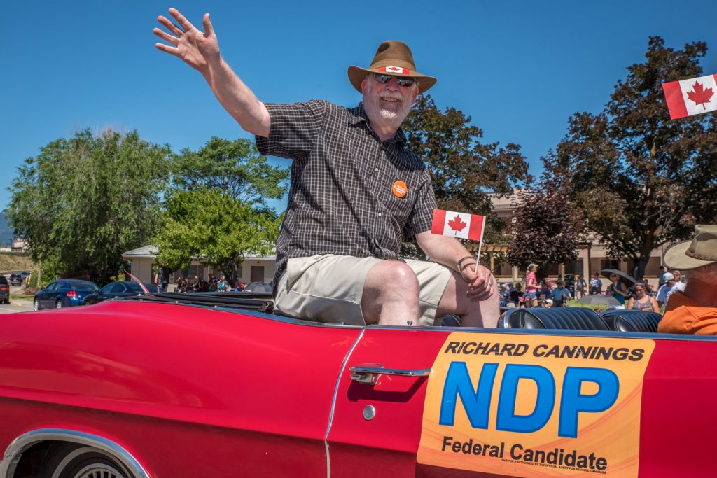 He's hoping for an orange wave, but federal NDP candidate Richard (Dick) Cannings rode a very red car in the Cherry Fiesta parade. (Richard McGuire photo)