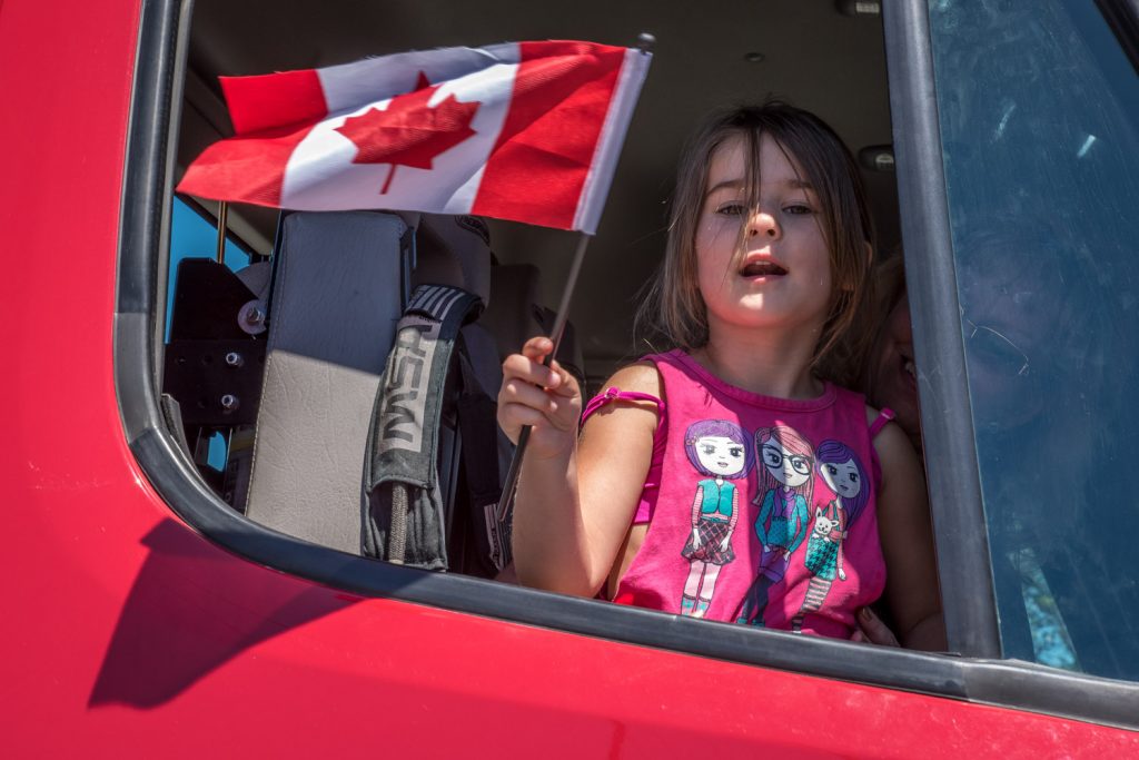 A young girl waves a Canadian flag from a fire engine in the Cherry Fiesta parade. (Richard McGuire photo)