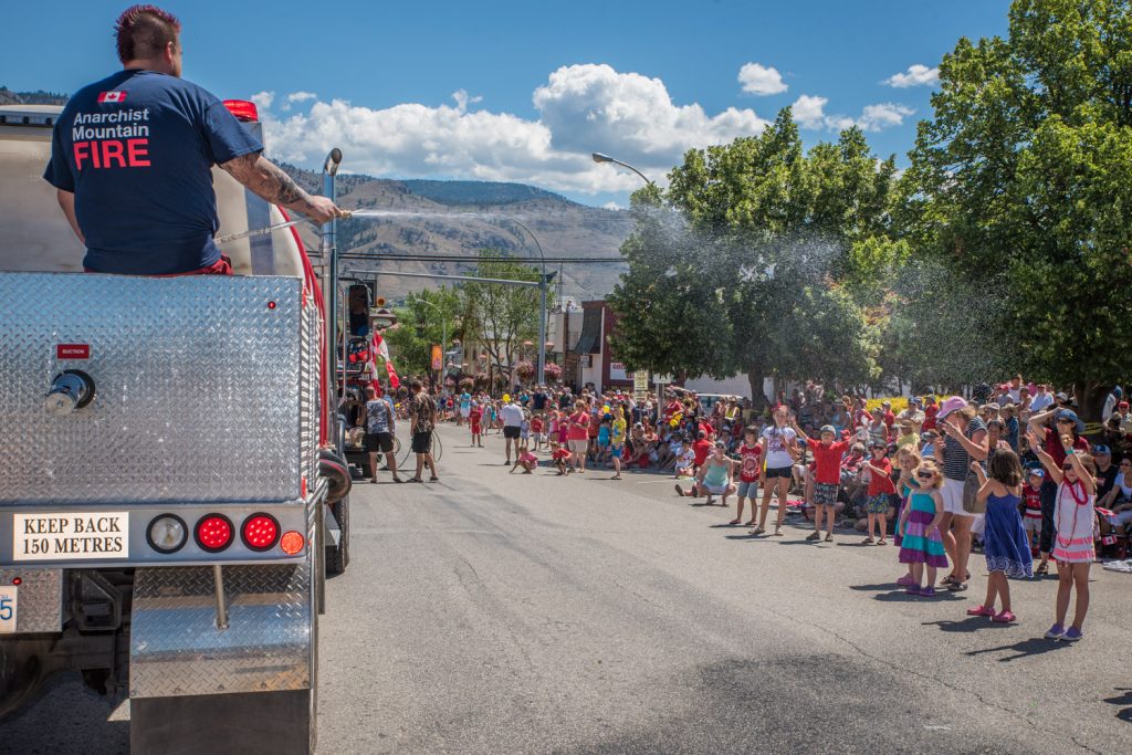 A member of the Anarchist Mountain Fire Department sprays spectators with water to cool them down in the warm sunshine during the Cherry Fiesta parade. (Richard McGuire photo)