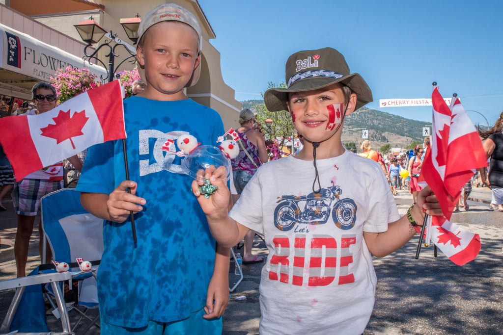 Elliot Jarrett, of Quesnel, (left) and Oscar Langballe, of Vancouver, were waving flags as the Cherry Fiesta parade passed along Main Street. (Richard McGuire photo)