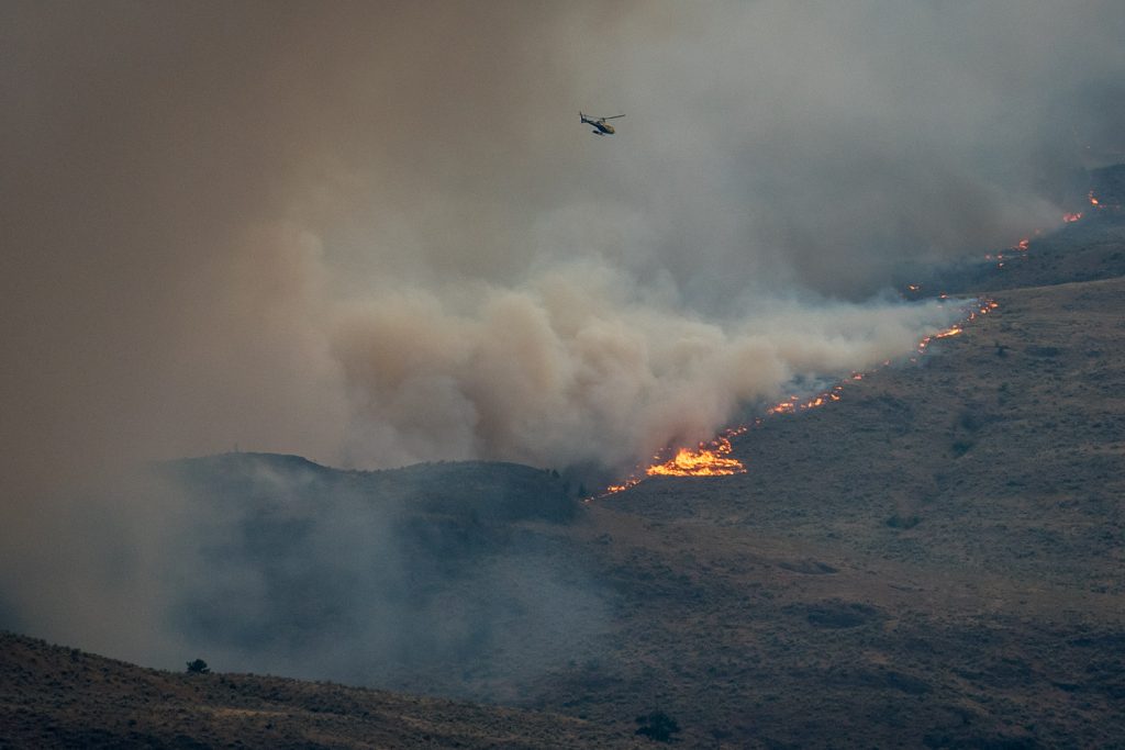 A helicopter flies through smoke and powerful winds by the Testalinden fire north of Osoyoos. B.C. Wildfire Service resources are spread thin with numerous fires in the area. This photo was taken at 7:01 p.m. Friday. (Richard McGuire photo)