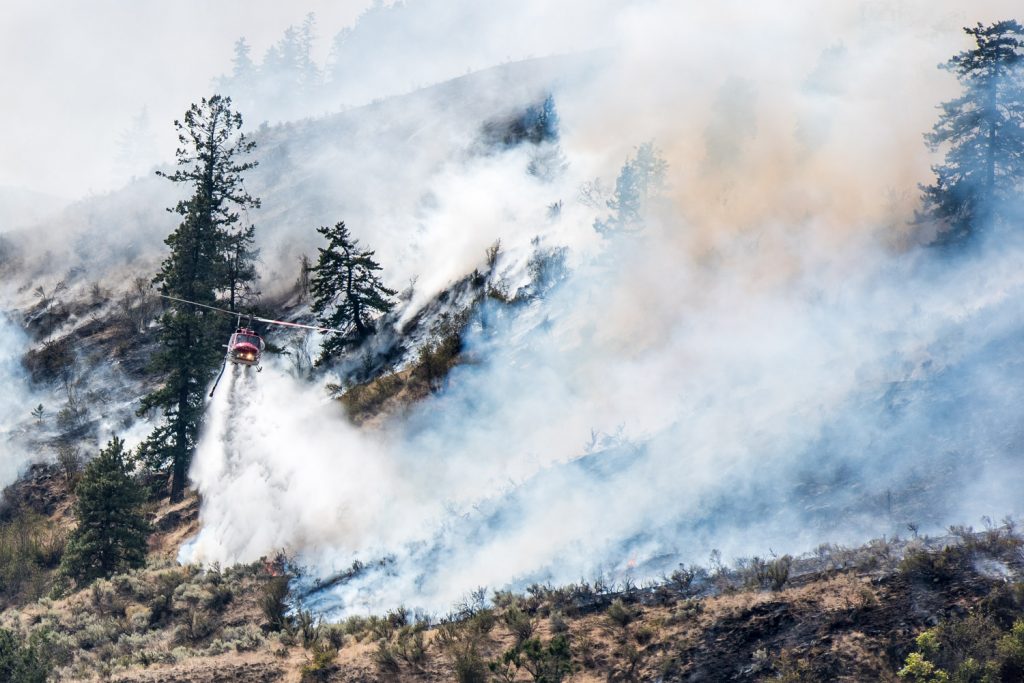A helicopter drops water from a nearby slough onto the Testalinden Creek fire near Road 20 and Highway 97 just after noon Saturday. (Richard McGuire photo)