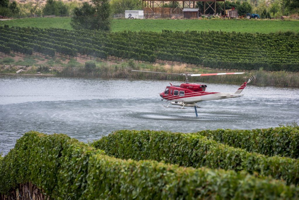 A helicopter picks up water at a nearby slough to drop on the Testalinden Creek fire near Road 20 and Highway 97. This photo was taken at 12:15 p.m. Saturday. (Richard McGuire photo)