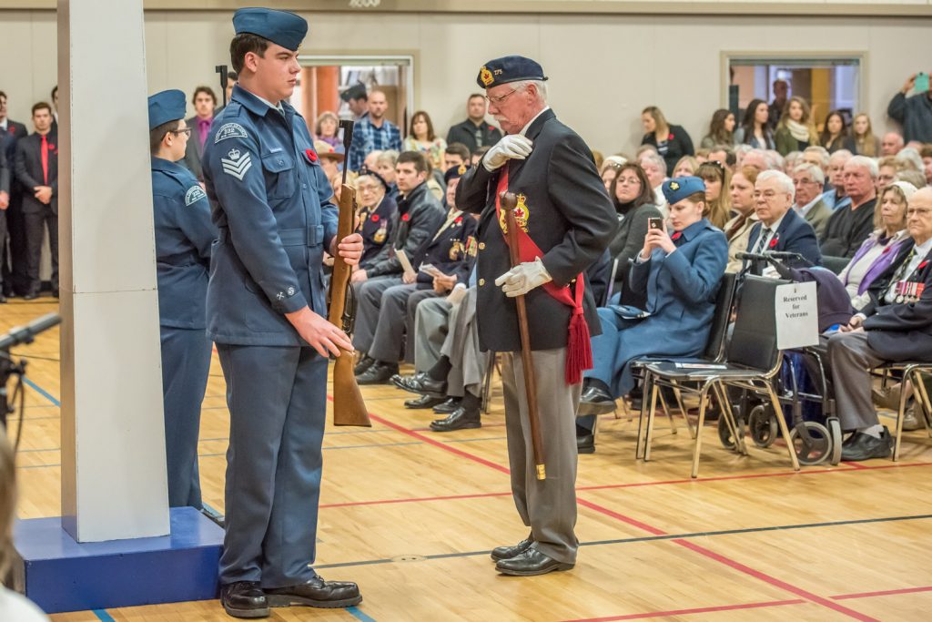 Sergeant-at-Arms Lew Taylor removes his poppy to lay it as an act of remembrance. (Richard McGuire photo)