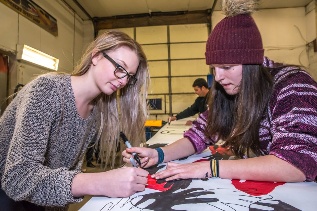 Lauren Schell (left) and Sarah Launier were among those making up posters and signs Monday evening to support keeping Osoyoos schools open. J.F. Launier, in background, offered up his JF Kustoms garage for the sign-making blitz in preparation for Tuesday's public consultation meeting with School District 53. (Richard McGuire photo)