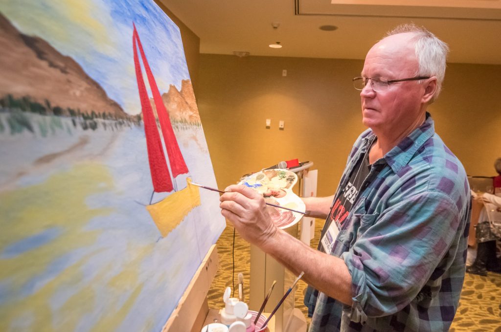 Alan Bleiken corrected the record when he was introduced as an artist, but he has more experience than most of the more than 50 people who turned out Saturday evening for the Paint and Sip fundraiser for the Osoyoos Lake Water Quality Society. Bleiken offered pointers to participants, who were given a canvas, acrylic paints and brushes and tasked with doing a painting inspired by Osoyoos Lake. (Richard McGuire photo)