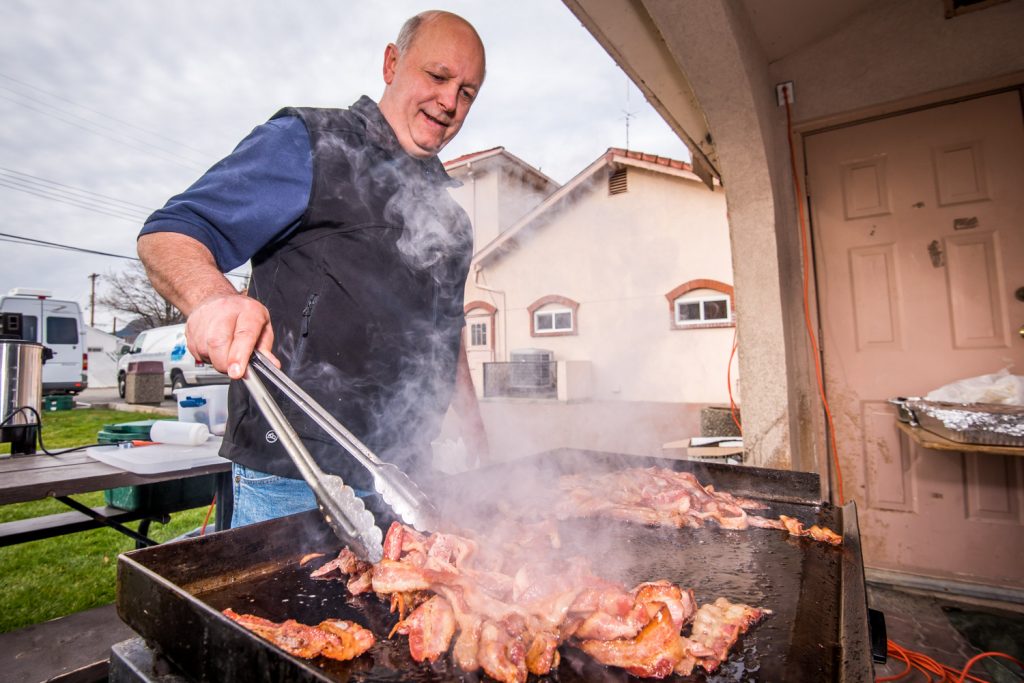 Doug Matthews sizzles up some bacon for the Rotary Pancake Breakfast. Matthews had one of the warmer jobs on a chilly morning. (Richard McGuire photo)