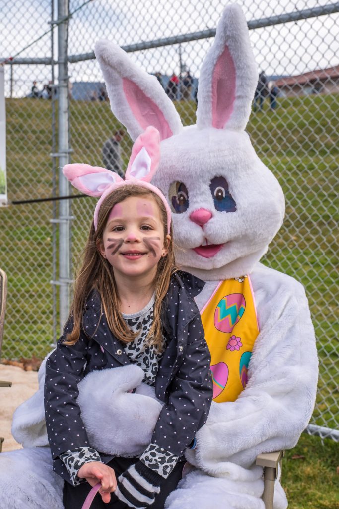 Wearing bunny ears and whiskers, Mila Keller, 5, sits on Easter Bunny's lap after the egg hunt. (Richard McGuire photo)