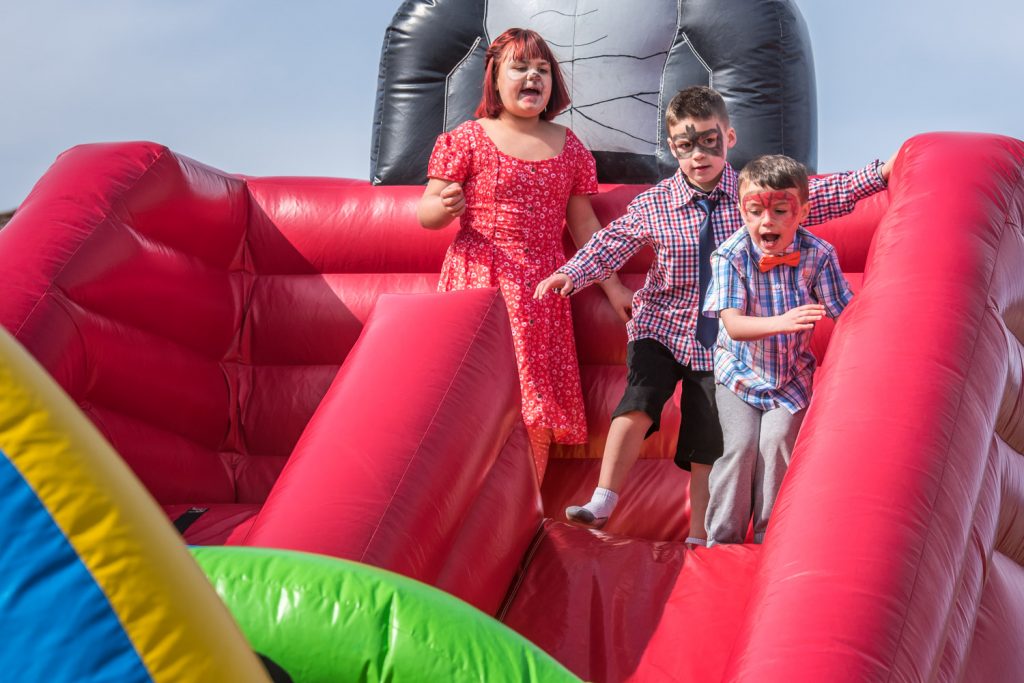 With faces painted, children prepare to jump down the slide on the bounce castle. (Richard McGuire photo)