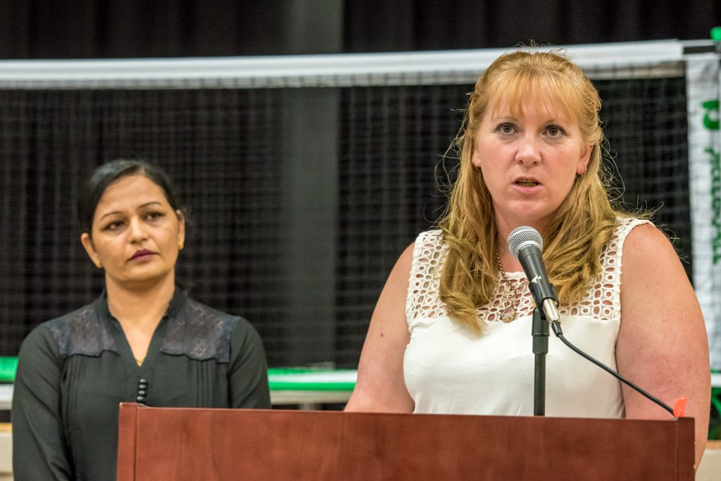 Brenda Dorosz, chair of the Osoyoos Independent School committee, updates members of the community on the progress being made to establish an independent high school At left, Kuldeep Rai, a committee member, waits to provide interpretation in Punjabi for Indo-Canadians attending. (Richard McGuire photo)