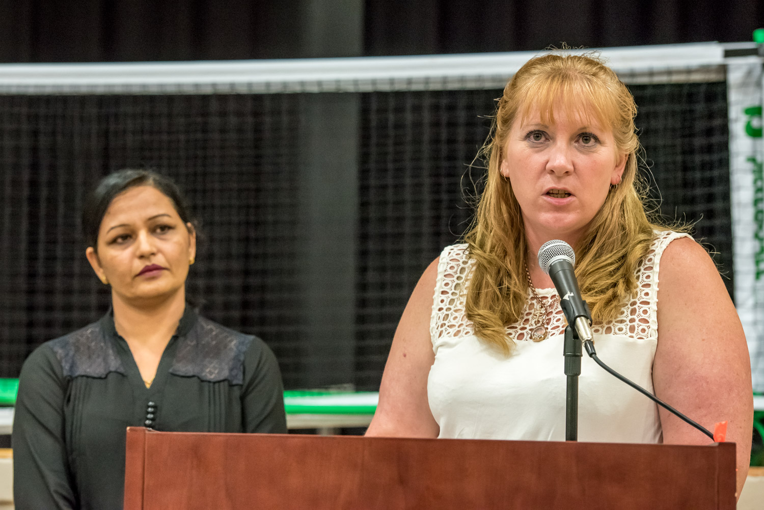 Brenda Dorosz, chair of the Osoyoos Independent School committee, updates members of the community on the progress being made to establish an independent high school At left, Kuldeep Rai, a committee member, waits to provide interpretation in Punjabi for Indo-Canadians attending. (Richard McGuire photo)