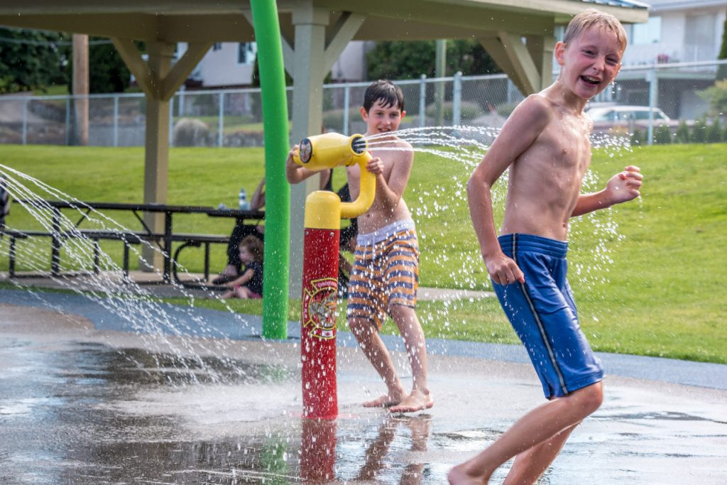 Lucas Butler, 9, (right) gets a cooling shower at the Osoyoos Splash Park from his friend, Luke Atkins, 9. The Town of Osoyoos held Family Splash Day on Wednesday afternoon at the park. (Richard McGuire photo)