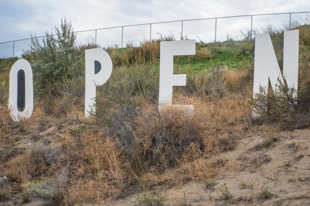 A large "OPEN" sign sits on top of the hill approaching Osoyoos Secondary School. The sign was made by Jamie Elder of Unity Osoyoos. (Richard McGuire photo)