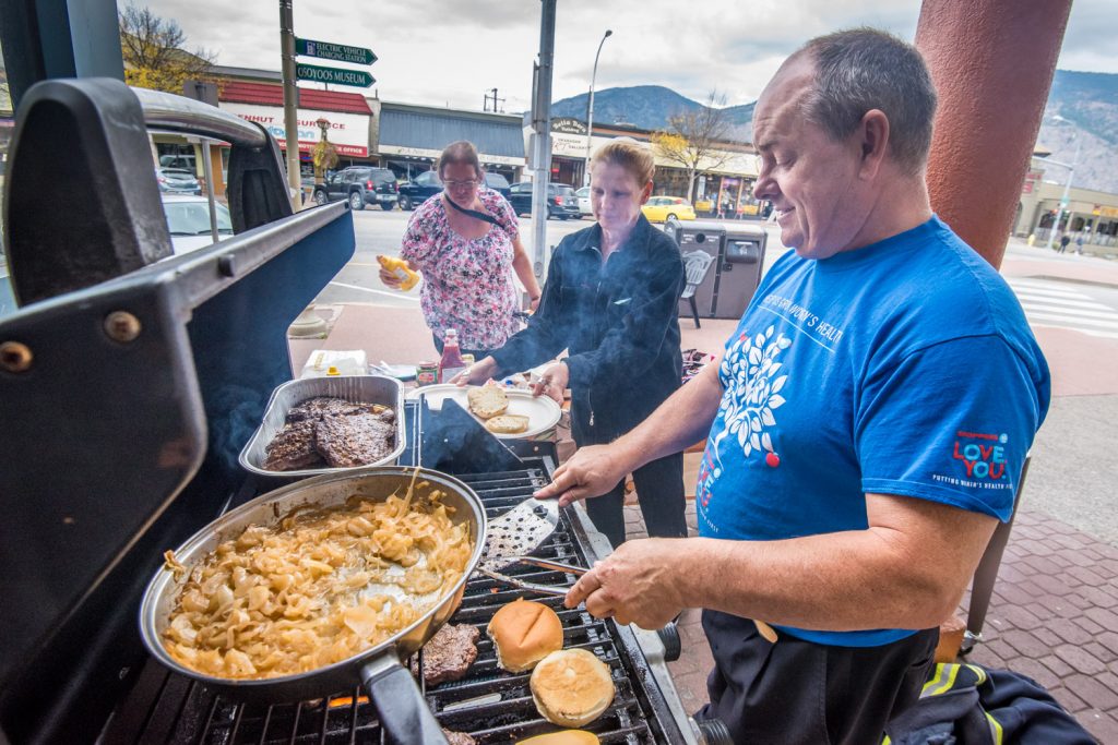 Trevor Long cooks burgers and onions while Brenda Andrews serves customers as the two Shoppers Drug Mart employees took part in BBQ for Hospice last Thursday. The store was selling burgers, chips and a drink with all the money raised going to the Shoppers Drug Mart Growing Women's Health Campaign and the Desert Valley Hospice Society. (Richard McGuire photo)