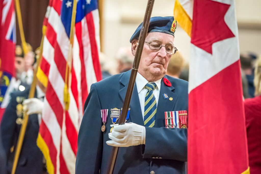 The colour party leaves the Sonora Community Centre carrying flags at the end of the service. (Richard McGuire photo)