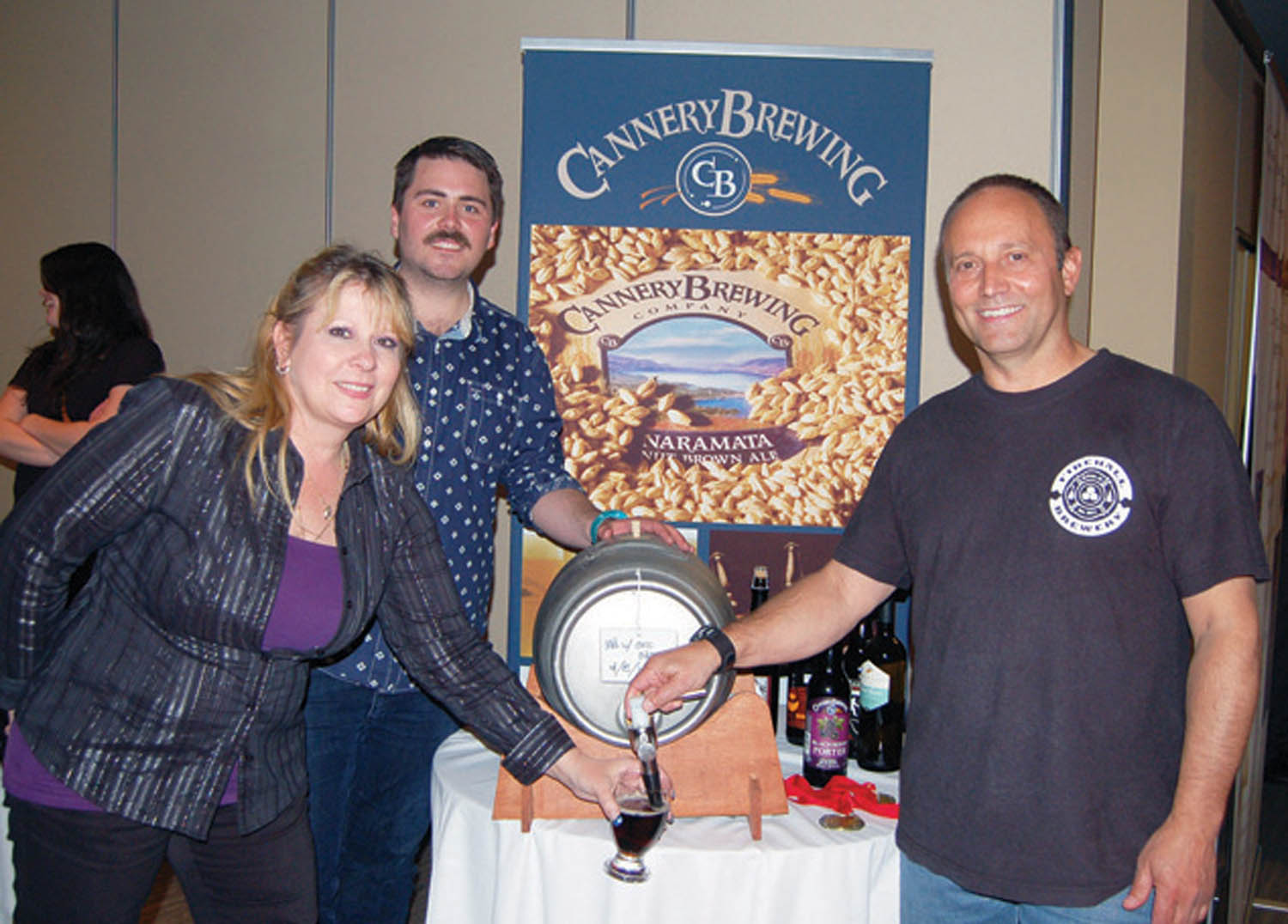 Diane Brockholm, of Tinwhistle Brewing Company, Ian Dyck of Cannery Brewing and Jim Rhuland of the Firehall Brewary, tap a glass of the “collaborale,” a beer specially brewed in collaboration by the three South Okanagan breweries. (Erin Christie photo)