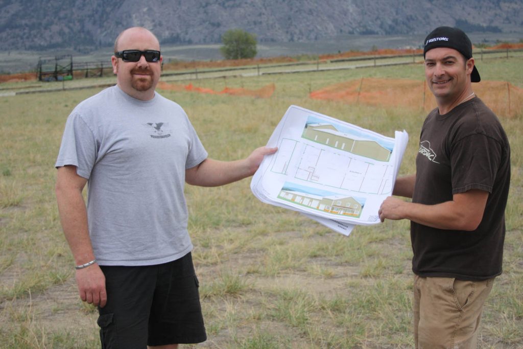 J.F. Launier (right), the longtime owner of JF Kustoms in Osoyoos, is looking forward to building a new state-of-the-art shop on a parcel of land next to the Osoyoos Airport. Launier is seen looking at detailed building plans with longtime friend and JF Kustoms employee Mike Richens. Construction on the new shop should begin within weeks after Town of Osoyoos council approved Launier’s rezoning application. (Keith Lacey photo)