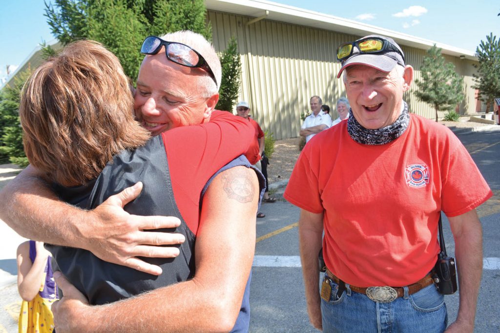 B.C. Premier Christy Clark gives a warm hug to Oliver Fire Department Chief Dan Skaros during her visit to Oliver this past Sunday morning. Clark, Boundary-Similkameen MLA Linda Larson and Steve Thomson, Minister of Forests, Lands and Natural Resource Operations, visited local residents following devastating fires that broke out Friday in Oliver. Looking on is Oliver Fire Department Deputy Fire Chief Bob Graham. (Lyonel Doherty photo)