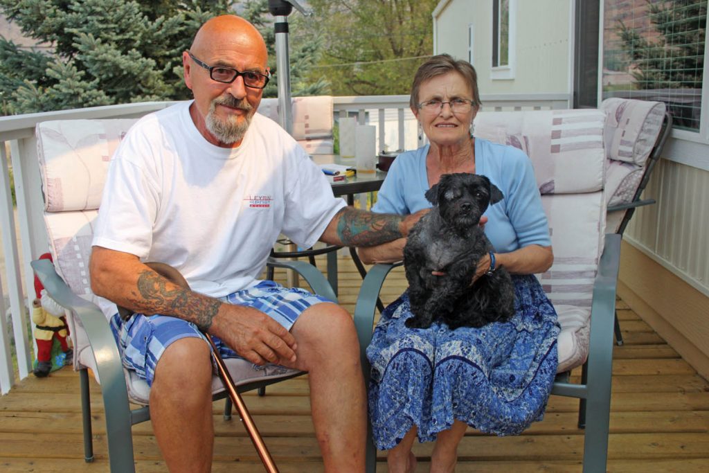 Osoyoos senior Ernie Demko and his pet dog Keiko were both rushed for emergency medical treatment after they were attacked by a vicious pit bull. Keiko lost his right eye, while Demko received numerous wounds from dog bites. Demko and Keiko are shown on the porch of their Osoyoos home recovering from their injuries with Demko’s wife Louise. (Keith Lacey photo)