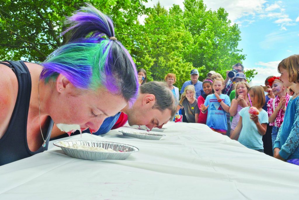 With hands behind their backs, Alena and David Zambrano bury their faces in tin foil dishes in an attempt to win the pie-eating contest. (Dan Walton photo)
