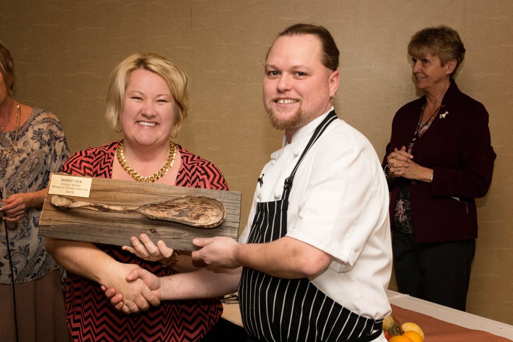 Tamara Aspell, executive director of Desert Sun Counselling & Resource Centre, congratulates Empty Bowls fundraiser winner of the People’s Choice Award, Damian Mischkinis.  Damien is the Chef de Cuisine from The Sonora Room at Burrowing Owl Winery. He prepared a lovely “Mushroom Veloute” for the event held on Nov. 14 at the Watermark Beach Resort in Osoyoos. The soup ladle on the award was hand carved and donated to the event by Butch Abel, from Rock Creek. The event raised more than $19,000 for programming at Desert Sun. Boundary-Similkameen MLA Linda Larson, who acted as emcee for the evening, looks on in the background. (Photo supplied) 