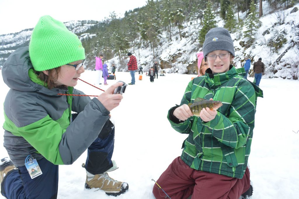 Tyler Algar (left) from Summerland takes a photo of friend Riley Hanratty’s perch that he caught during a morning of ice fishing on Yellow Lake recently. Next weekend, the Osoyoos Boys & Girls Club is sponsoring its inaugural Kids Gone Wild Ice Fishing Derby. A total of 25 kids from across the South Okanagan, including several from Osoyoos, will travel to Lambly Lake northwest of Kelowna, to spend a day ice fishing and enjoying a pleasant outdoor experience. (Lyonel Doherty photo)