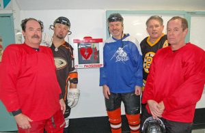 From left, Doug Hume, Jeff Crowley, Marty Whiteman, Bryan Coles and Steve Arstad gather around the newly installed AED in the Oliver arena lobby. This group of five hockey players worked as a team to save fellow player Harold Cox, who was technically dead from a massive heart attack during a recent game. One zap from the AED, in combination with CPR, brought Cox back to life.  (Lyonel Doherty photo)