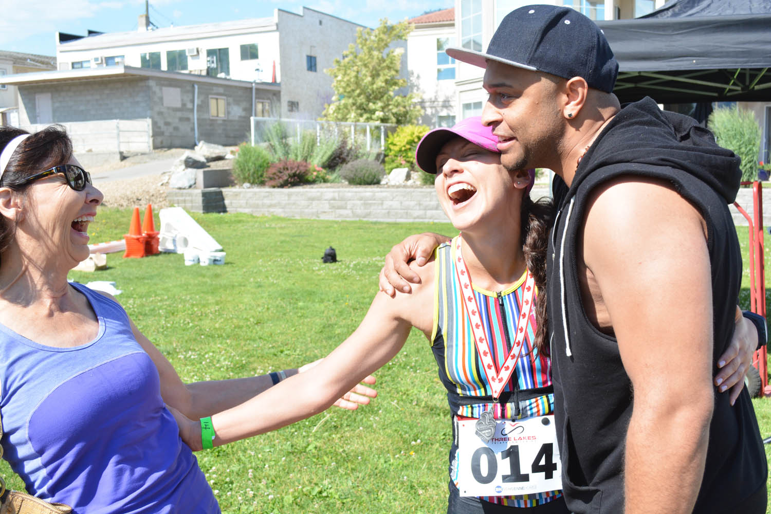 Megan Fretter from White Rock is congratulated by fiance Jerome Morley and grandmother Donna Mortimer from Osoyoos after she crosses the finish line in the Osoyoos Lake Loop Triathlon on June 28. (Lyonel Doherty photo)