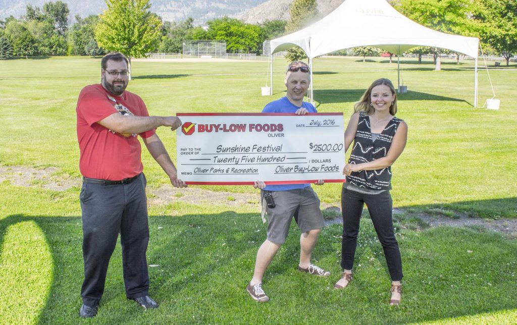 To take a big chunk out of the costs for this year’s Sunshine Festival, Buy-Low Foods manager Tyler Gludovatzand, left, hands off a cheque for $2,500 to parks and recreation staffers Kyle Fossett, reception clerk, and Natalie Korsovetski, program supervisor. (Dan Walton photo)