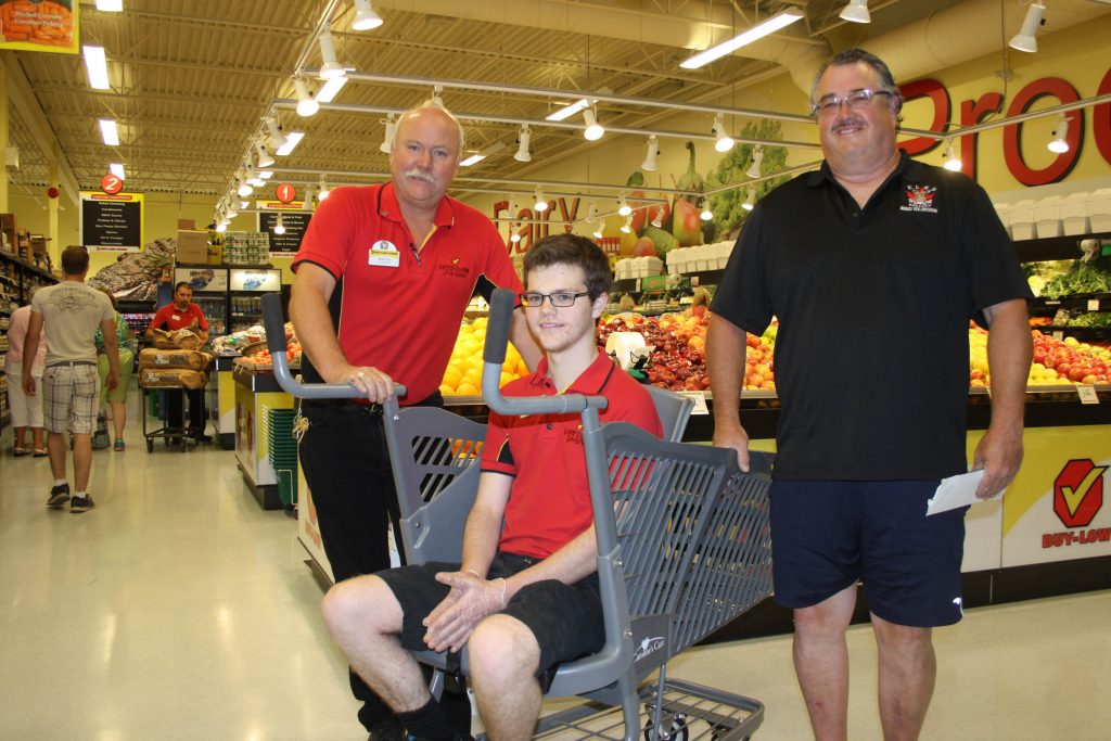 Thanks to fundraising efforts by members of the Osoyoos Elks Club, the Osoyoos Buy-Low Foods can now offer the usage of Caroline’s Cart to customers. The specialized cart will allow customers with mobility and special needs to pick up their groceries conveniently. On hand last week when the cart officially arrived at the store were Buy-Low manager Brian Fry (left), Osoyoos Elks Club president Ken Thibault and grocery store employee Kyle McBurney, 19. (Keith Lacey Photo)