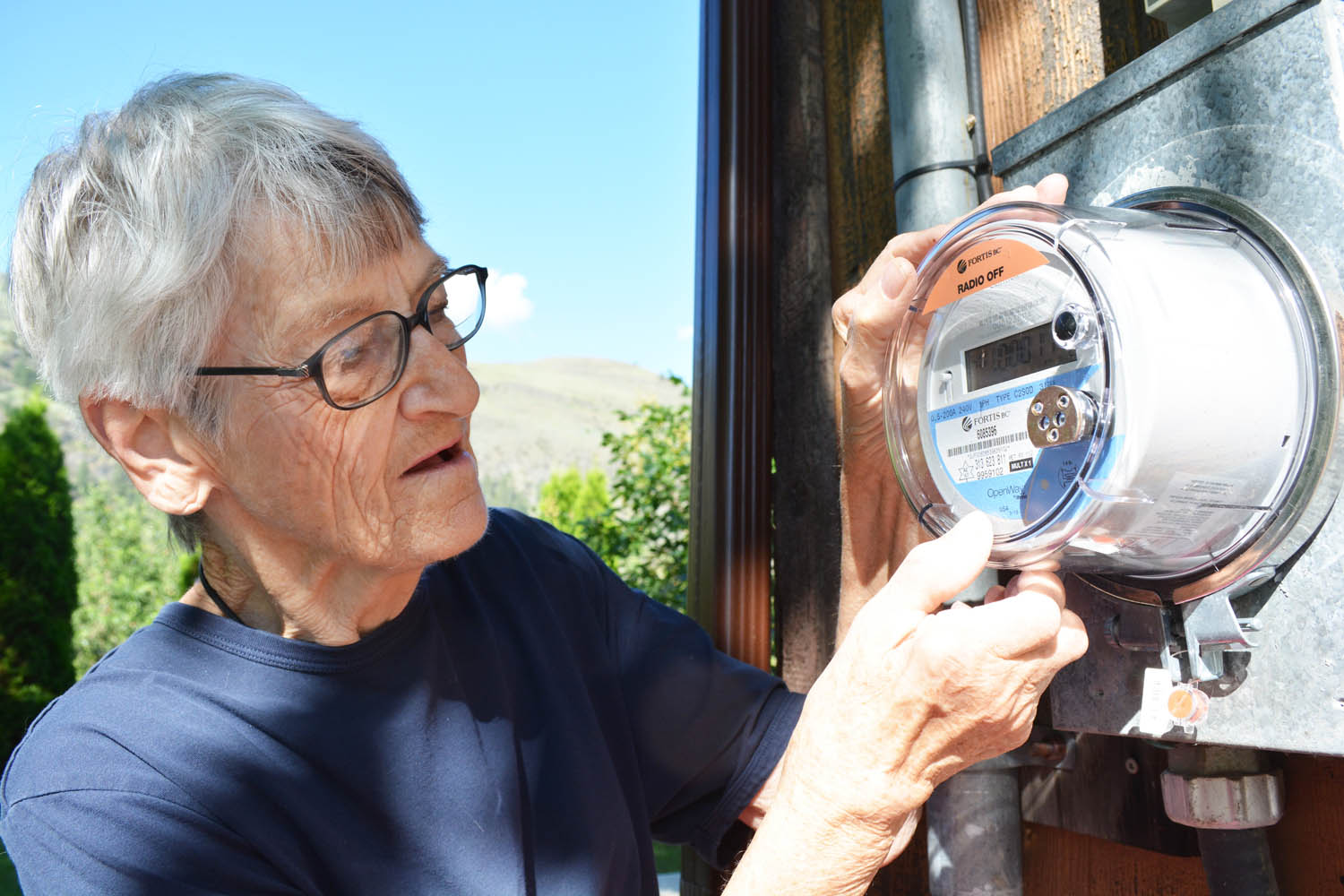 Frances Lepp, who lives on Road 18 between Osoyoos and Oliver, says she has a sensitivity to electromagnetic fields and fears that the new “smart meter” will make her medical problems worse. Here, she looks at her radio-off meter that was recently installed. (Lyonel Doherty photo)