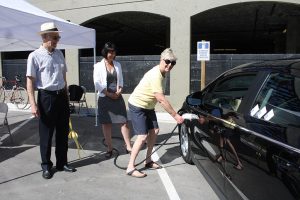 Photo by Keith Lacey Coun. Sue McKortoff (right) connects a cable to charge an electric car at the new charging station near Gyro Park, while Coun. Michael Ryan and vehicle sales professional Tracy Cameron look on.