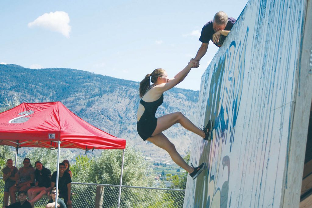 John Seminoff, the veteran OSS teacher who brought the Storm the Wall event to Osoyoos, helps a competitor over the wall. Seminoff is pleased the event will continue at SOSS in Oliver next year. (Keith Lacey photo)