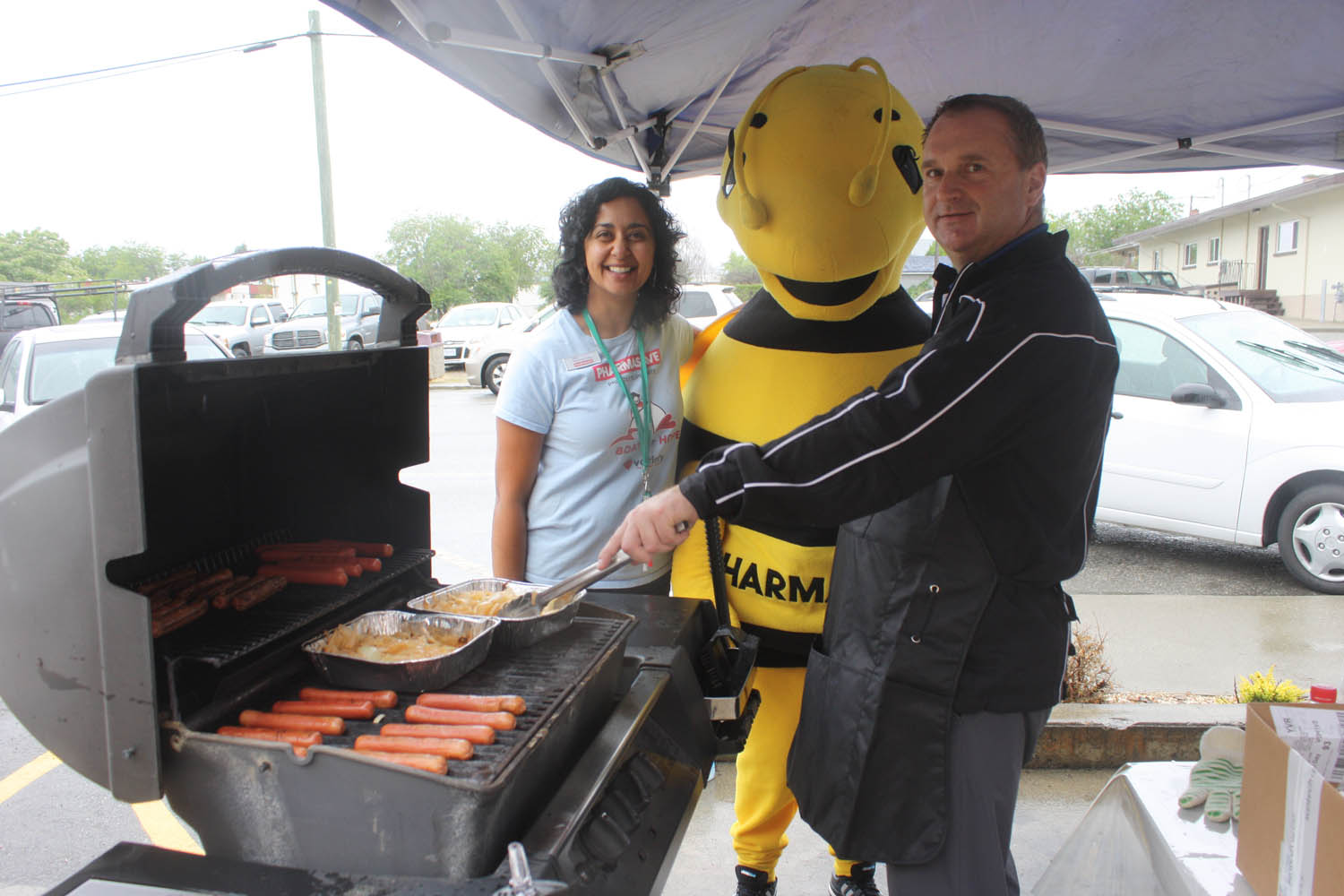 Pharmasave Osoyoos held its fifth annual Boat for Hope Barbecue last Friday. Even though there was plenty of rain and cloudy skies all day, the fundraising barbecue raised more than $350 for the Variety Club through the sale of hot dogs, chips and pop. Cooking up some tasty hot dogs were Pharmasave co-owner Jolly Gill and her husband Lee Sapach. They were joined by the store’s mascot. (Keith Lacey photo)