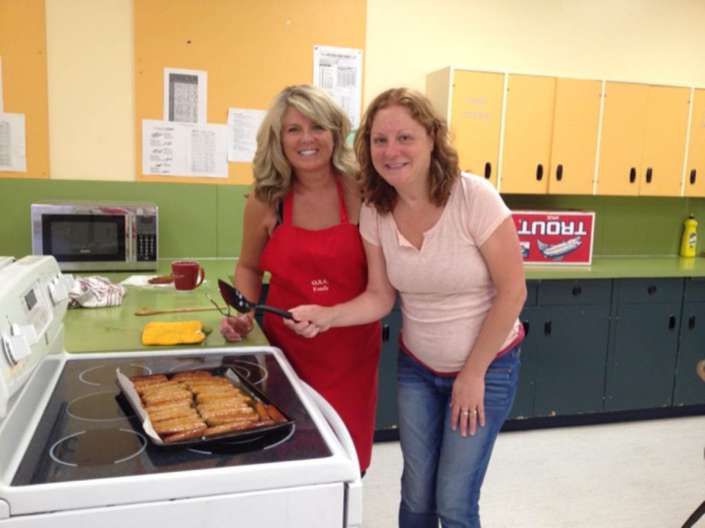 SHARLENE FERNANDES Both grocery stores in Osoyoos - Buy-Low Foods and AG Foods - donated huge amounts of food so students at Osoyoos Secondary School could hold a special pancake breakfast last Wednesday. Pictured, Adrienne Mailey, a member of the Parents Advisory Council, and Sharlene Fernandes prepare sausages for dozens of students. (Photo supplied)