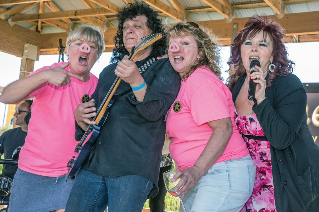 Wearing pig noses, Helen Tidder (left) and Cheryl Trsek (third from left) joined others on stage at the end of Pig Out in May at Covert Farm where Wined It Up, a cowboy rock band was performing. Guitarist Ken Repkow and singer Mikie Spillett performed some lively music for the two pigs and other guests, who were up dancing. Tidder and Trsek were visiting from the Lower Mainland. (Richard McGuire photo)
