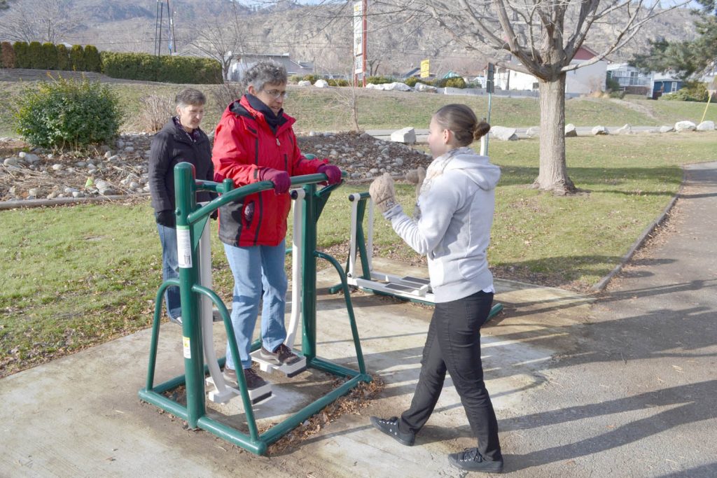 Julia Munro learns to use a piece of outdoor exercise equipment from Jenessa Maddalena this past Saturday at Lions Park in Oliver as part of the inaugural Day of Wellness sponsored by Grant Storzuk, the owner and operator of the Okanagan Physiotherapy and Active Wellness Centre, that has offices in Osoyoos and Oliver. (Trevor Nichols photo)
