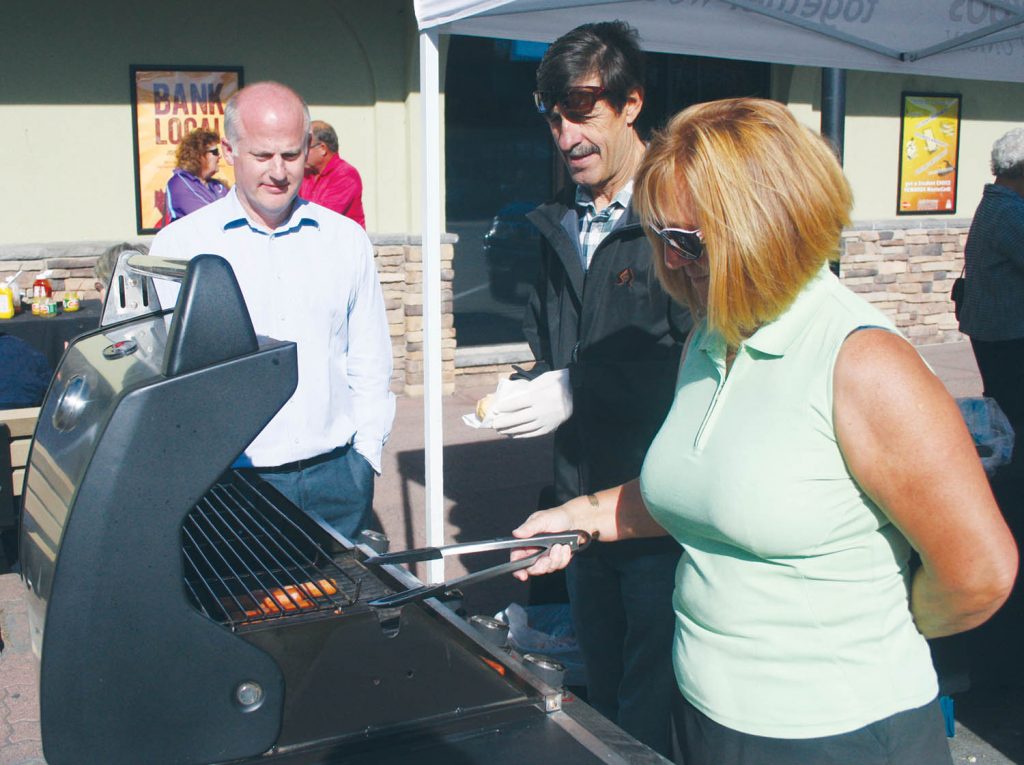 The Osoyoos Credit Union, which has been part of the Osoyoos community for several decades, helped celebrate national Credit Union Day by sponsoring a luncheon barbecue outside their branch on Main Street last Thursday afternoon. Staff and members of the board of directors from the credit union cooked and served hot dogs. Cookies were also served. Board members Kathy Gudewill and Alex Nunes are shown serving up a tasty hot dog to one of the dozens of people who dropped by. (Keith Lacey photo)