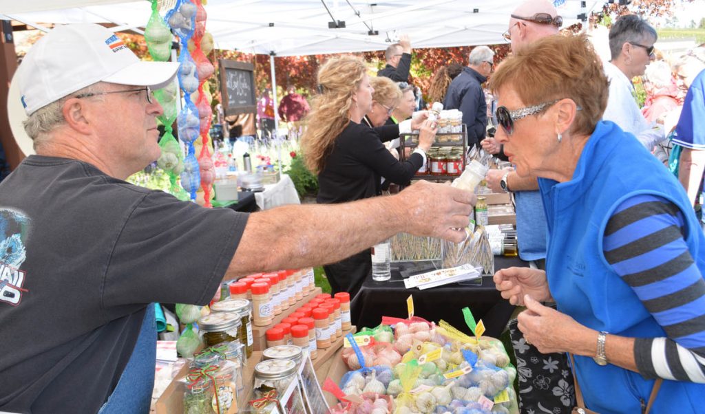 Adele Jenkins from Osoyoos smells some garlic offered by Gord Wiffen from Russell Farms in Vernon during the annual Garlic Festival at Hester Creek Estate Winery on Saturday, Oct. 3. (Lyonel Doherty photo)