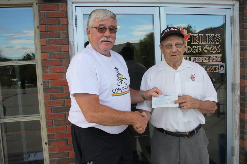 Members of the Osoyoos Elks Club and Osoyoos Royal Purple prepared dinner for RCMP officers and support staff participating in this year’s Cops for Kids event. Elks Club past president LeRoy Olson presented a cheque for $500 to Cops for Kids ride captain Julio Krenz. (Keith Lacey photo)