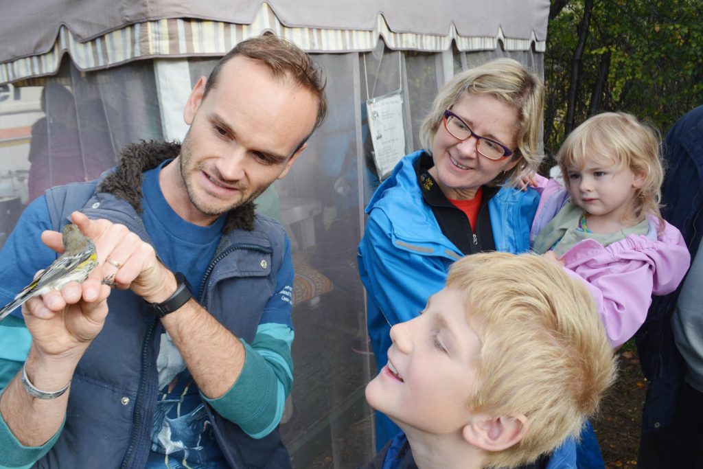 Wildlife biologist Jason Bieber shows off a warbler to the family of Amanda Erickson (mother), Anya MacPhail (daughter) and Liam MacPhail (son) during Bird Migration Day at the Vaseux Lake Bird Observatory on Sept. 25. (Lyonel Doherty photo)