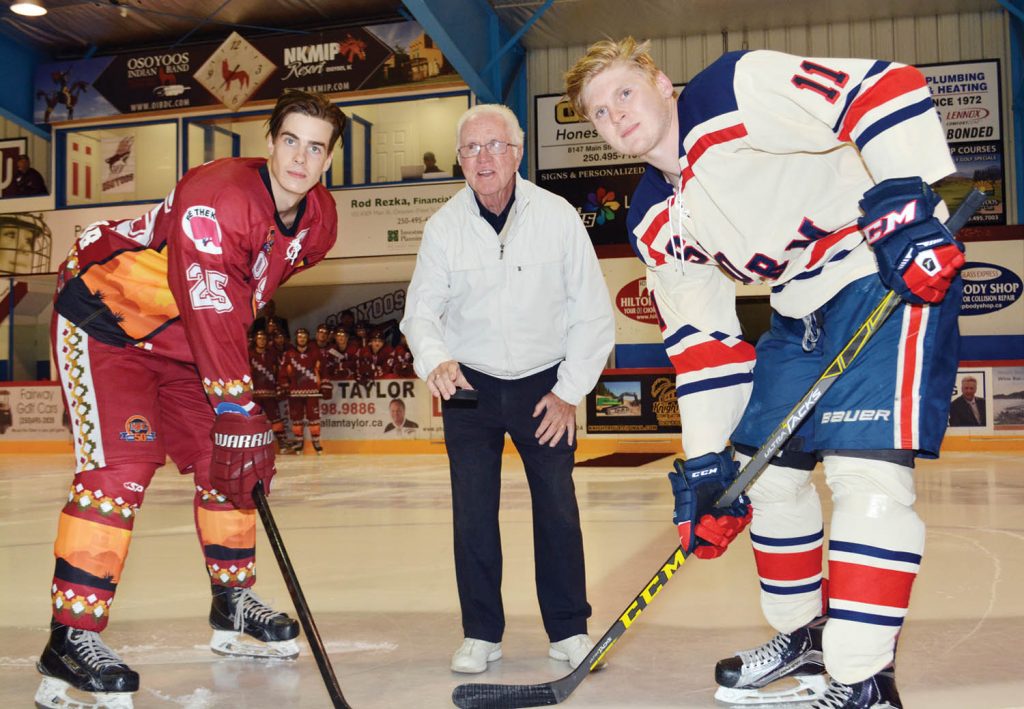 World champion goalie (1955 Penticton Vees) Ivan McLelland prepares to drop the puck for the start of the Osoyoos Coyotes home opener against the Kamloops Storm last Saturday. At left is Coyote Daniel Stone facing off against the Storm’s Kole Comin. The Coyotes defeated the Storm 6-3, with five, third-period goals. The story of why McLelland turned down a contract offer to play in the Montreal Canadiens’ organization is featured in the new book called In the Moment: Real Life Stories of Hope & Inspiration. McLelland was signing copies of the book prior to and after the game on Saturday. (Lyonel Doherty photo)