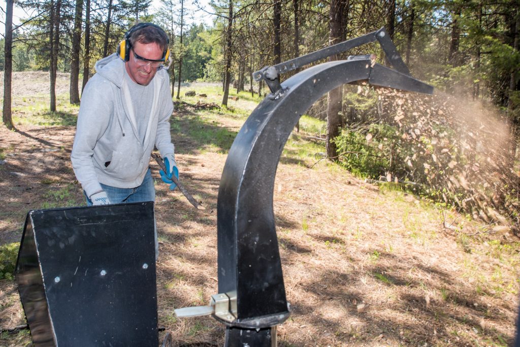 Brent Gilbey feeds a wood chipper with branches in a community effort to reduce fire hazards. Members of the Anarchist Mountain Community held an event on Saturday for National FireSmart Preparedness Day. Volunteers cleaned up brush and other fire hazards at Sasquatch Pond Park. (Richard McGuire photo)