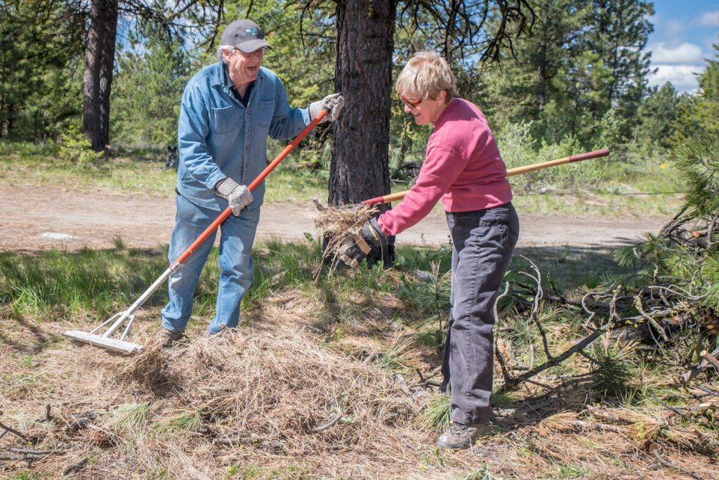 hris De Jaham and Debbie Dundass rake up brush in a community effort to reduce fire hazards. Members of the Anarchist Mountain Community held an event on Saturday for National FireSmart Preparedness Day. Volunteers cleaned up brush and other fire hazards at Sasquatch Pond Park. (Richard McGuire photo)